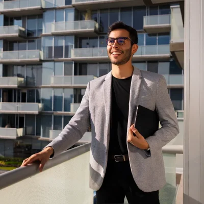 Close-up de dois executivos, um homem e uma mulher, segurando documentos e conversando em frente a edifícios modernos, simbolizando o papel do administrador de condomínio na gestão administrativa e financeira do empreendimento.