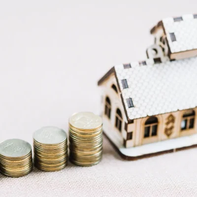 Moedas ao lado de casa simbolizando taxa de condomínio.