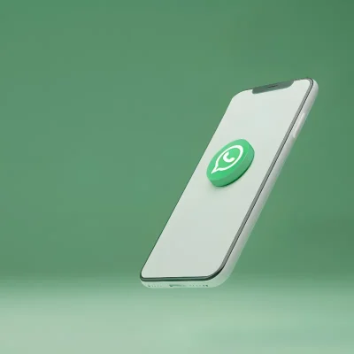 Smartphone branco inclinado com o logotipo verde do WhatsApp em 3D centralizado na tela, em um fundo verde suave. A imagem representa a ferramenta de comunicação mais utilizada, o WhatsApp em condomínios, destacando sua popularidade e agilidade, mas também a necessidade de regras claras e moderação. A utilização profissional e segura requer o estabelecimento de limites legais e práticos e a consideração de alternativas especializadas como o Group COM.