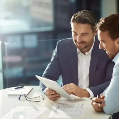 Reunião empresarial com dois homens analisando documentos, vendas para administradoras