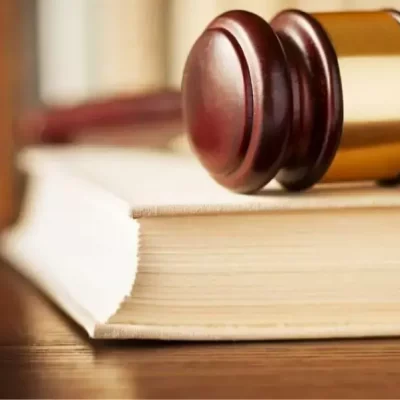 Imagem de um livro de leis com um martelo sobre ele, representando o glossário de legislação condominial e suas diretrizes para a administração de condomínios.