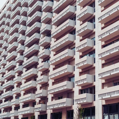 Fachada de um grande edifício moderno com muitas varandas em fileiras uniformes, representando um condomínio edilício.