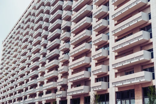 Fachada de um grande edifício moderno com muitas varandas em fileiras uniformes, representando um condomínio edilício.
