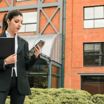 Profissional usando celular em frente a prédio corporativo