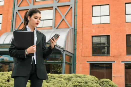 Profissional usando celular em frente a prédio corporativo