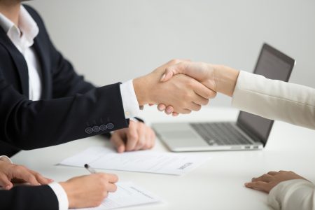 hr handshaking successful candidate getting hired at new job closeup - RH Tech