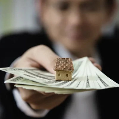 Miniatura de casa sobre notas, simbolizando inadimplência condominial