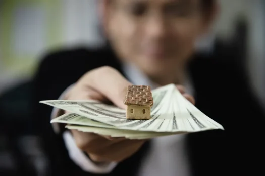Miniatura de casa sobre notas, simbolizando inadimplência condominial