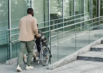 homem subindo ramba com cadeira de rodas respeitando a lei de acessibilidade em condominios residenciais group software