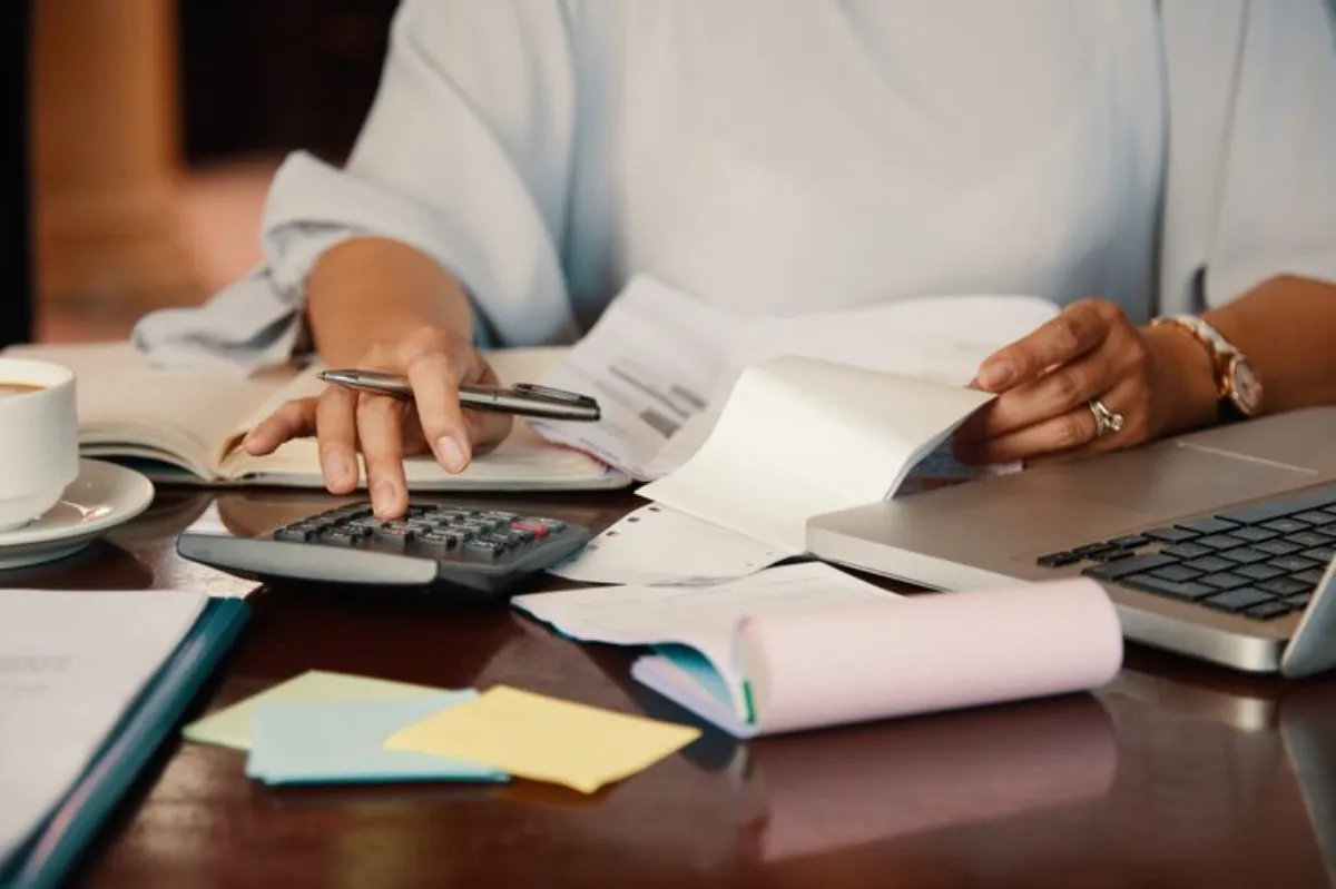 Pessoa calculando contas com notebook e documentos sobre a mesa, representando a gestão financeira e que um condomínio não emite nota fiscal