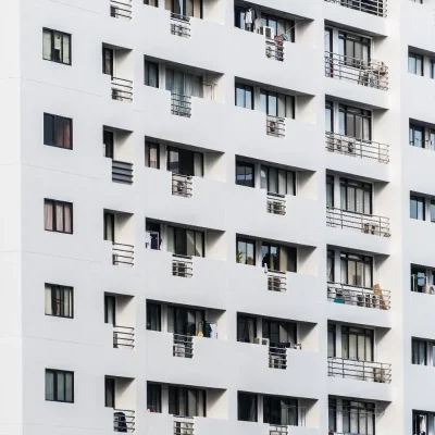 Fachada de um prédio de apartamentos moderno e branco, com diversas varandas e janelas, simbolizando um condomínio residencial e a responsabilidade da administradora na gestão do edifício.