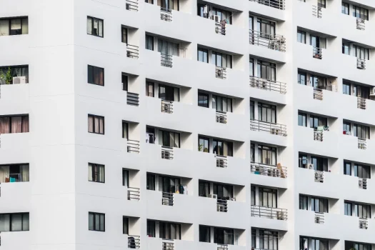 Fachada de um prédio de apartamentos moderno e branco, com diversas varandas e janelas, simbolizando um condomínio residencial e a responsabilidade da administradora na gestão do edifício.