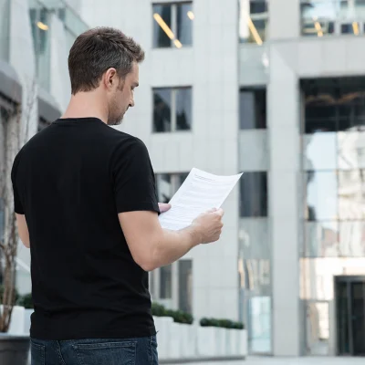 Síndico morador lendo documento em frente ao prédio