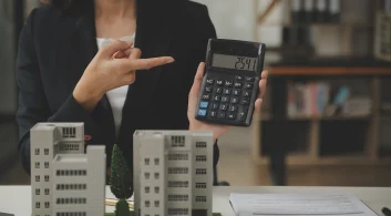Mulher aponta calculadora ilustrando a tributação do condomínio