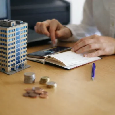 Mesa com moedas e maquete ilustrando cobrança garantida