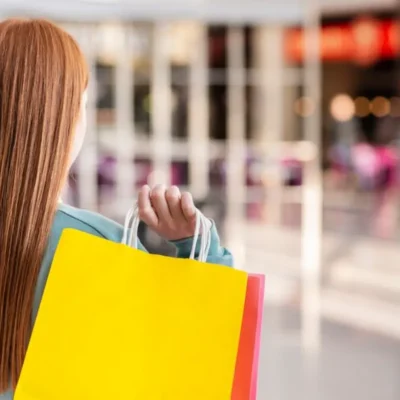 Indicadores de vendas em shoppings com consumidora carregando sacolas em centro comercial
